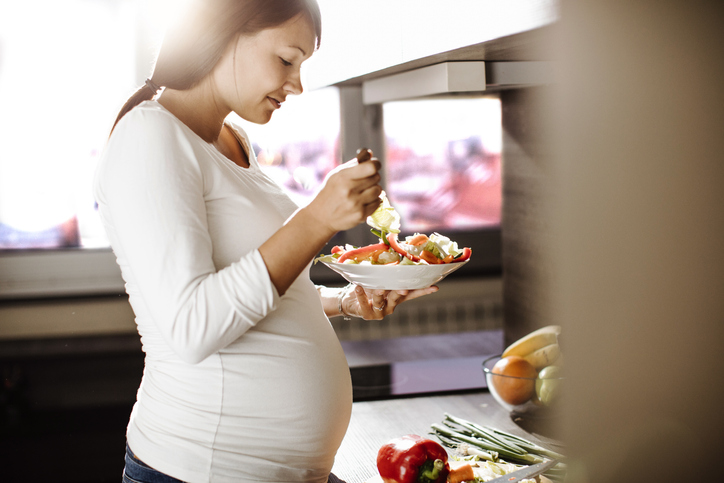 Future mother eating healthy food in the kitchen .