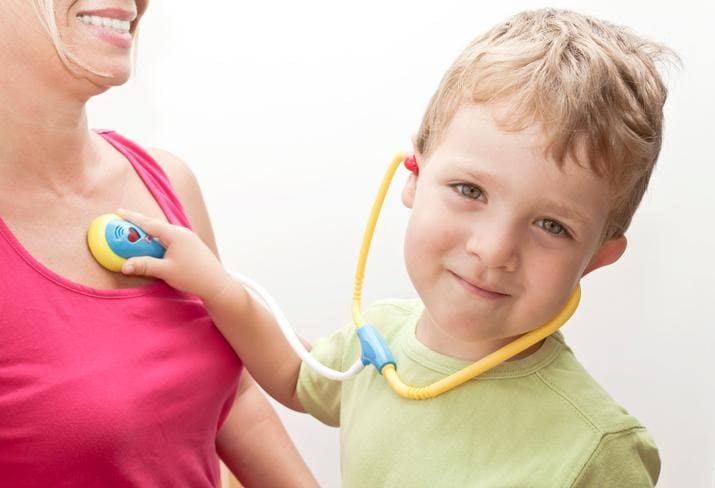 Cute boy playing doctor with his mother as patient