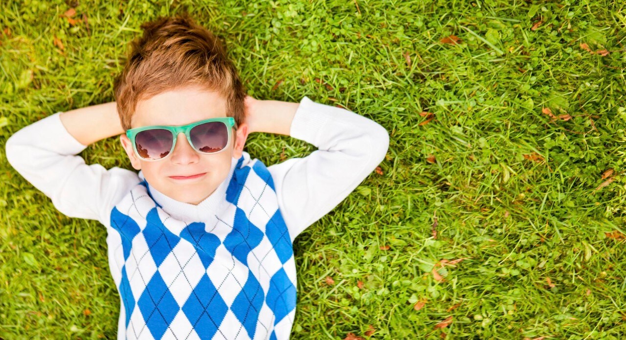 Portrait Of A Boy Wearing Sunglasses Relaxing On Green Grass