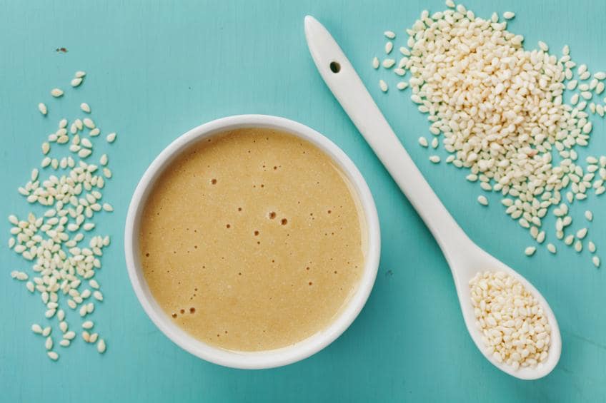 Homemade tahini or tahina, paste from ground sesame seeds on blue vintage surface, top view