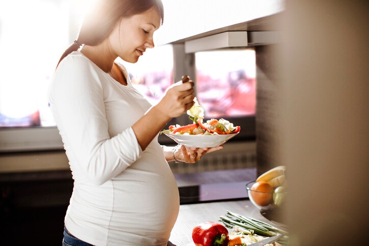 Future mother eating healthy food in the kitchen .
