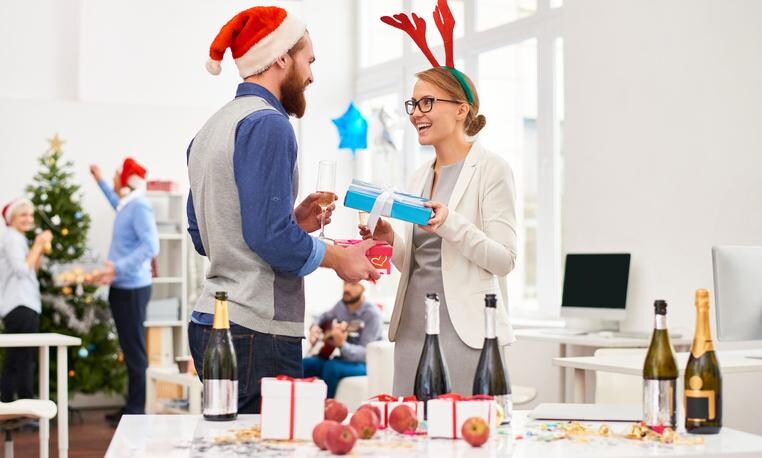Friendly office workers giving presents to each other at office party